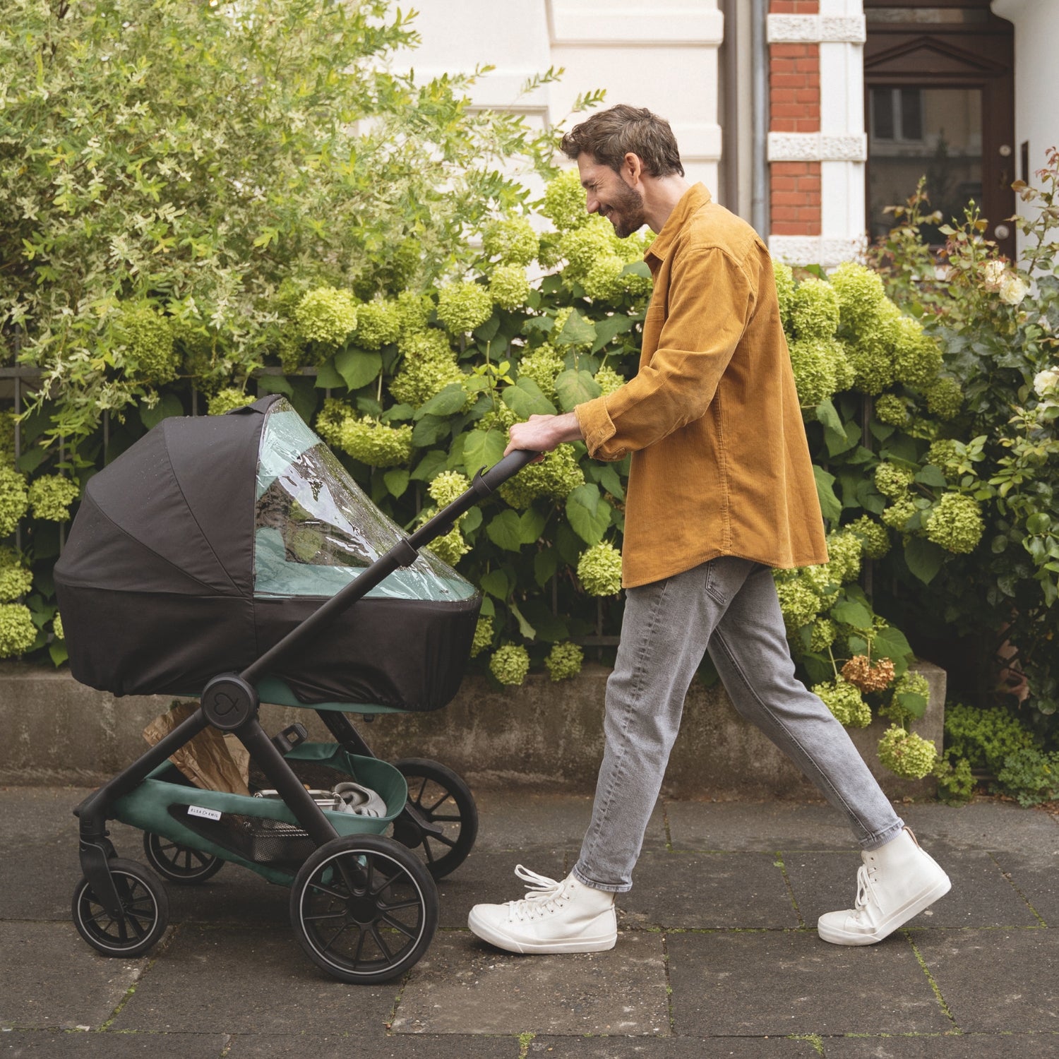 Vater mit Kinderwagen und Regenverdeck