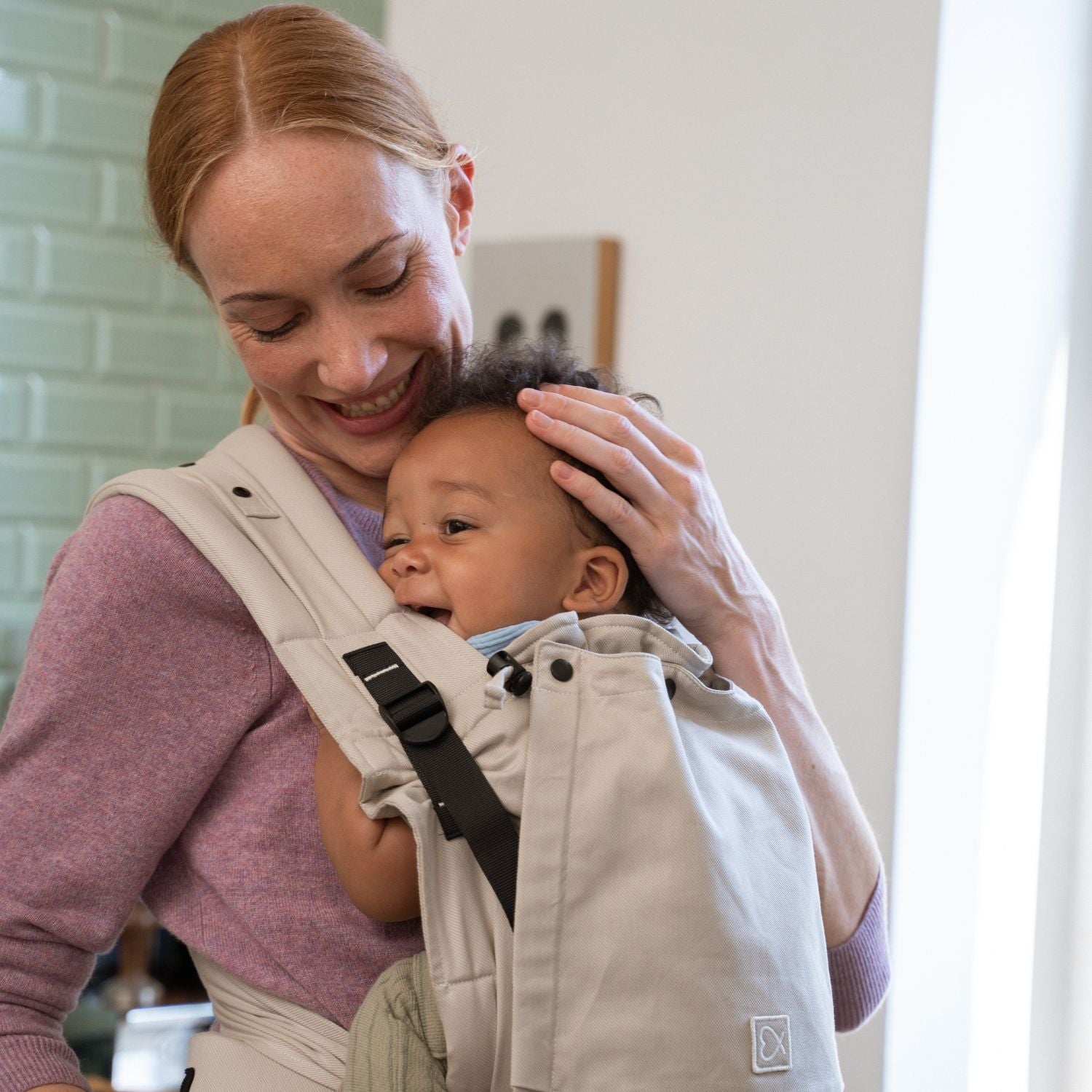 Mutter trägt ihr Kind in der ELSA & EMIL Babytrage in #farbe_kängurubeige