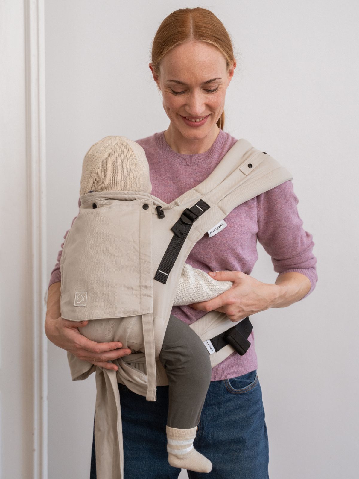 Mutter trägt das Baby mit der Halfbuckle in #farbe_kängurubeige in der Seitentrageweise